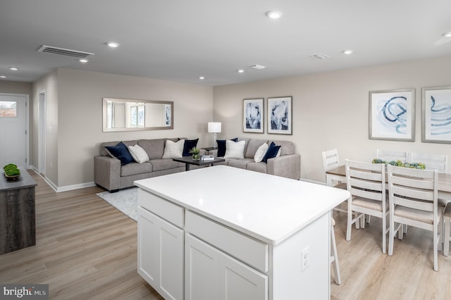 kitchen with white cabinets, a kitchen island, and light wood-type flooring