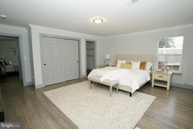 bedroom with dark hardwood / wood-style flooring, crown molding, and a closet