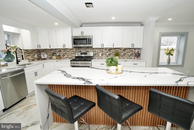 kitchen featuring light stone counters, sink, a spacious island, and appliances with stainless steel finishes