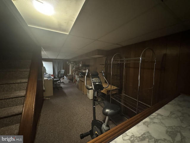 gym with carpet flooring, a paneled ceiling, and wooden walls