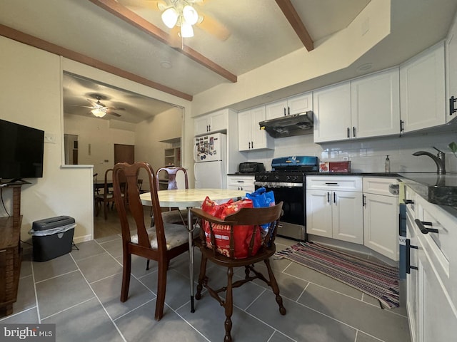 kitchen with white cabinets, white refrigerator, dark tile patterned floors, and stainless steel range oven