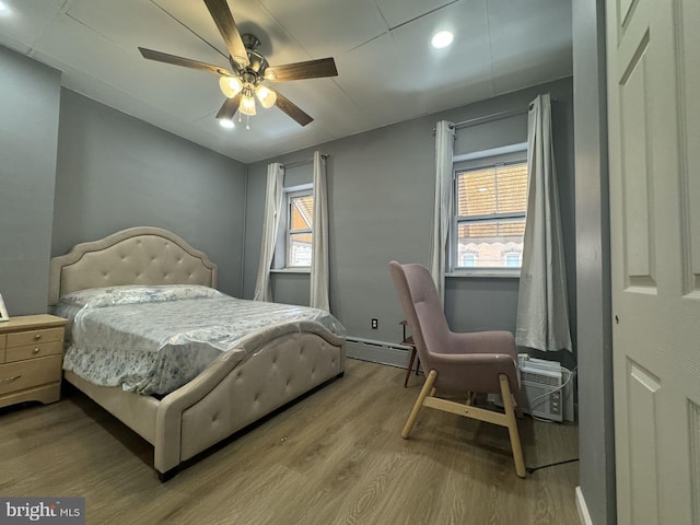 bedroom featuring light hardwood / wood-style floors, a baseboard radiator, and ceiling fan