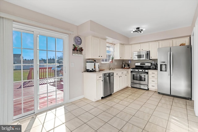 kitchen featuring white cabinetry, a healthy amount of sunlight, light tile patterned floors, and stainless steel appliances