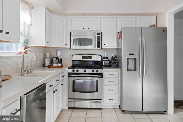 kitchen with sink, stainless steel appliances, light tile patterned floors, backsplash, and white cabinets