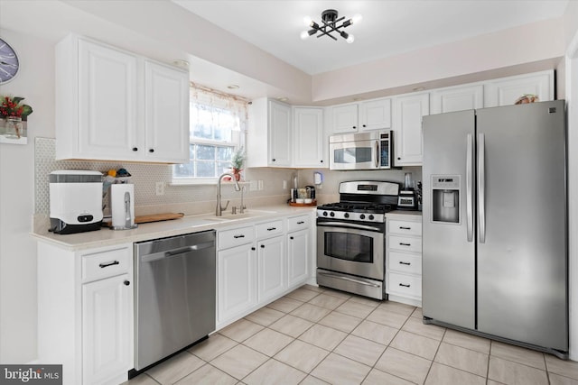 kitchen with white cabinets, sink, decorative backsplash, appliances with stainless steel finishes, and light tile patterned flooring