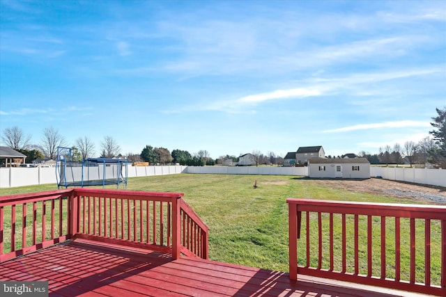 wooden terrace featuring a trampoline and a yard