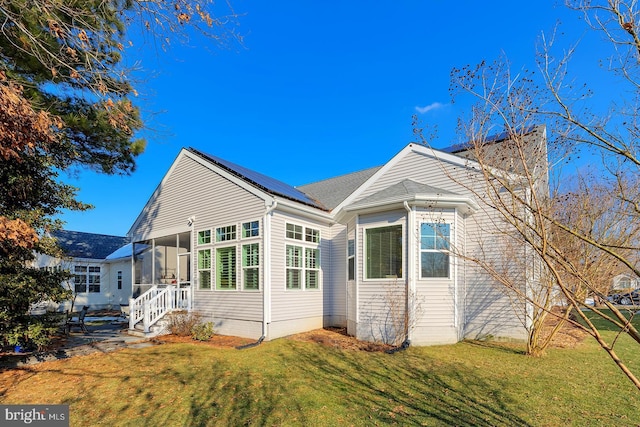 view of side of property with a sunroom, a yard, and solar panels