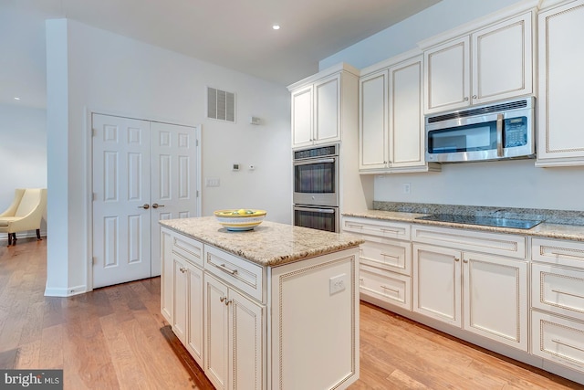 kitchen featuring light stone countertops, stainless steel appliances, a center island, and light wood-type flooring