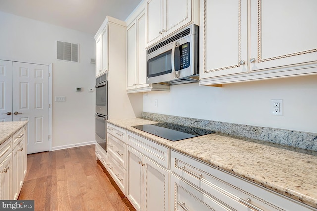 kitchen featuring light stone counters, appliances with stainless steel finishes, and light hardwood / wood-style floors