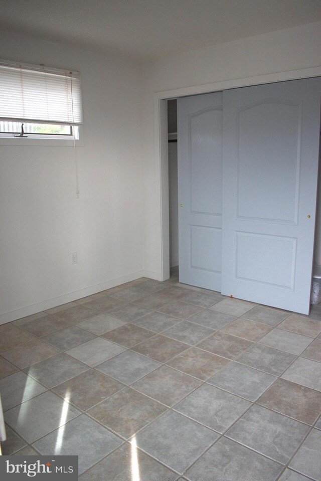 unfurnished bedroom with light tile patterned floors and a closet