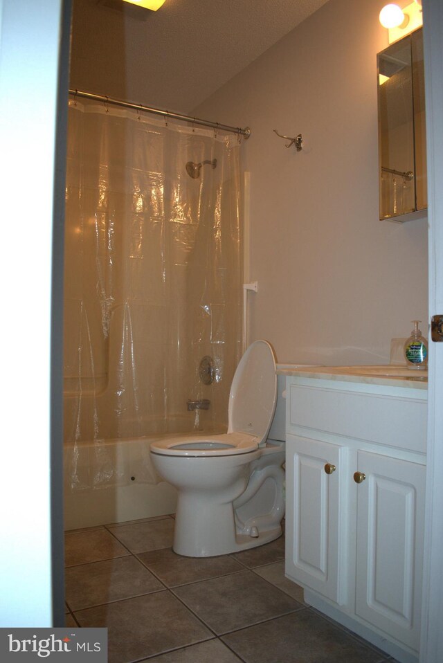 bathroom with tile patterned flooring, shower / bath combination with curtain, toilet, and a textured ceiling