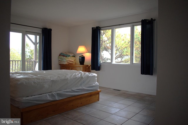 tiled bedroom featuring access to outside and multiple windows