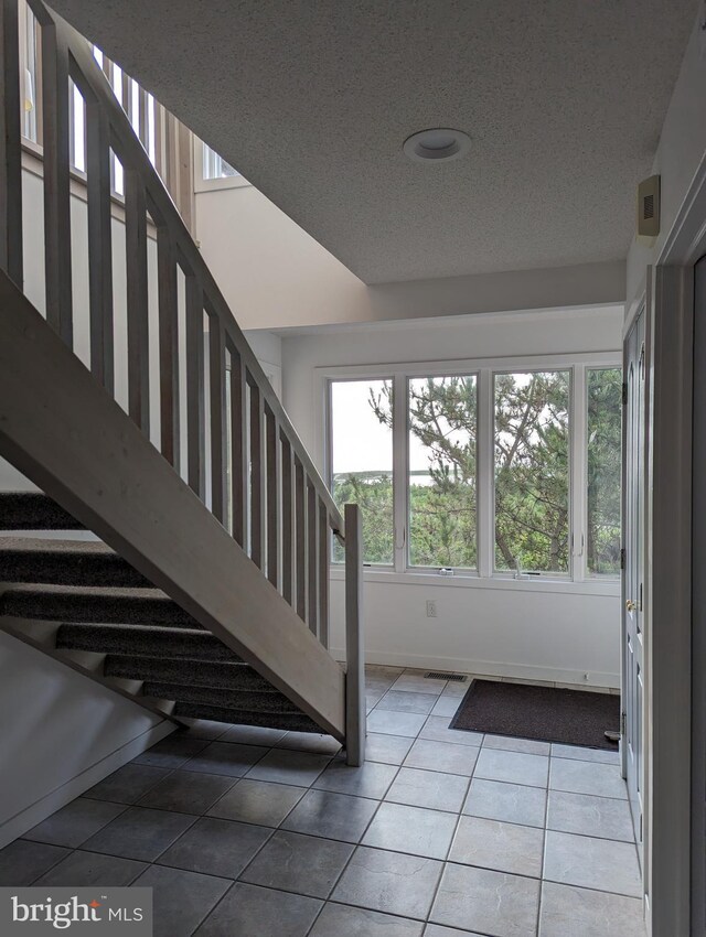 stairway featuring tile patterned flooring and a textured ceiling