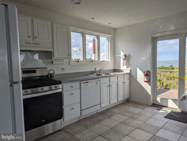 kitchen with white appliances, ventilation hood, sink, light tile patterned flooring, and white cabinetry