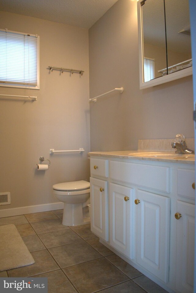 bathroom featuring tile patterned flooring, vanity, a textured ceiling, and toilet