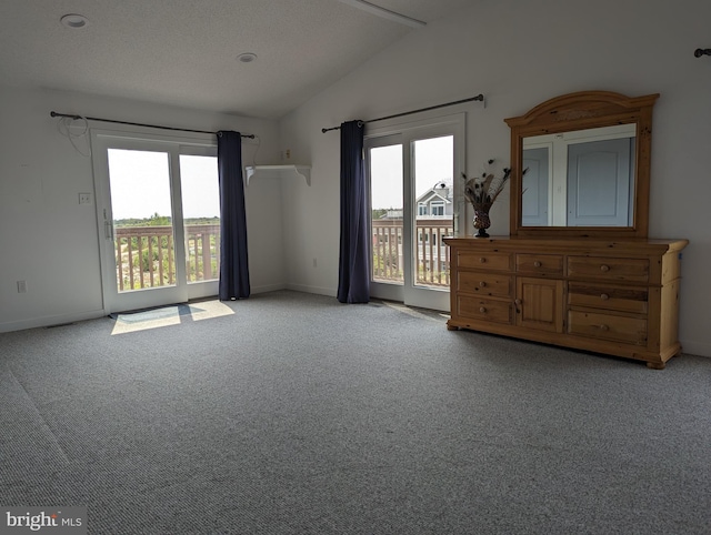 carpeted empty room with a textured ceiling, a healthy amount of sunlight, and lofted ceiling