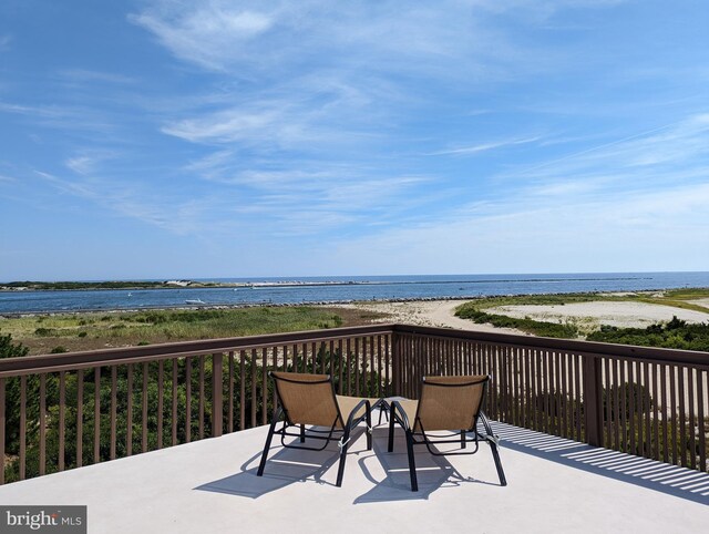 wooden terrace featuring a water view and a view of the beach