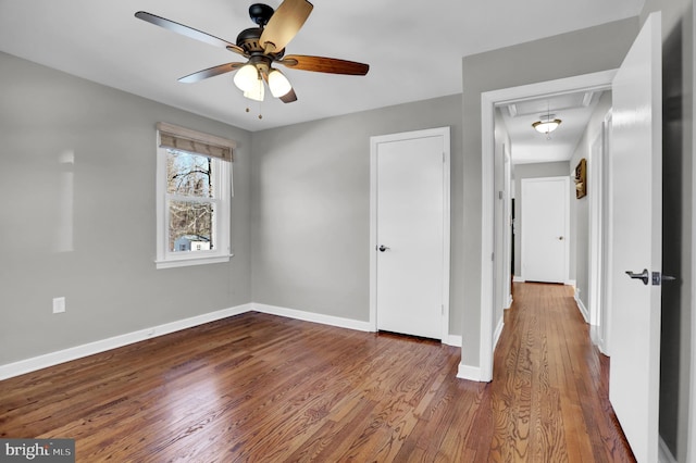 unfurnished bedroom with ceiling fan, wood-type flooring, and a closet