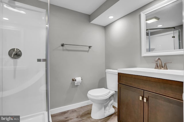 bathroom featuring hardwood / wood-style flooring, toilet, vanity, and walk in shower