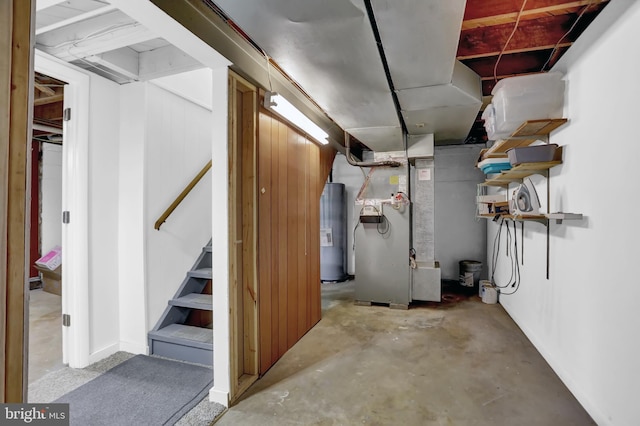 basement featuring electric water heater, heating unit, and wood walls