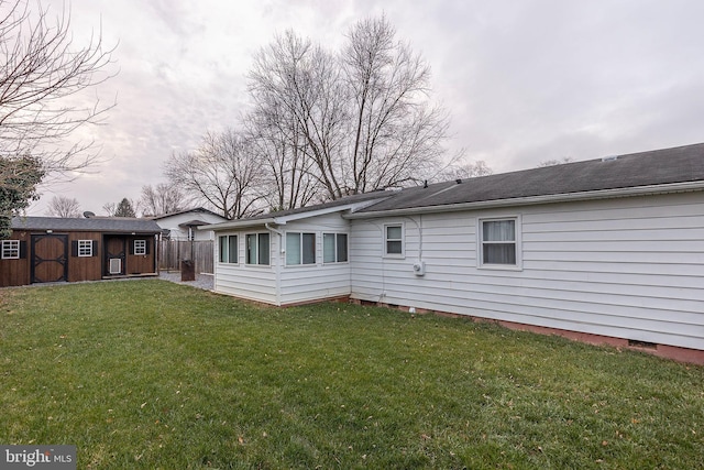 rear view of house featuring a lawn and a storage unit