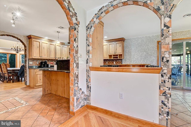 kitchen with light brown cabinetry, tasteful backsplash, hanging light fixtures, and a notable chandelier