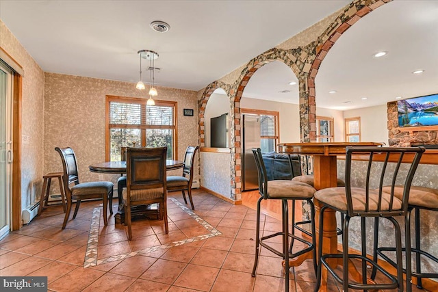 dining room featuring baseboard heating, a fireplace, and light tile patterned flooring