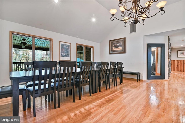 dining space featuring a chandelier, hardwood / wood-style flooring, and high vaulted ceiling