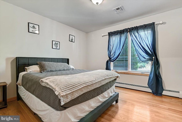 bedroom featuring light hardwood / wood-style flooring and a baseboard heating unit