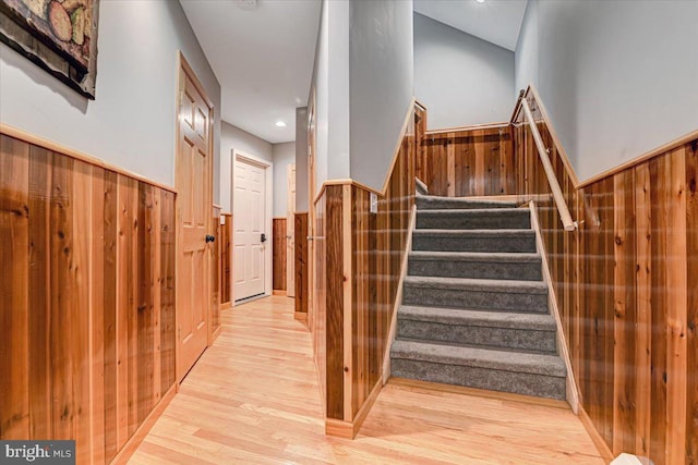 stairway with hardwood / wood-style floors and wood walls