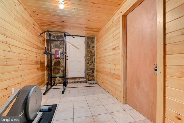 exercise room with light tile patterned floors, wooden walls, and wooden ceiling