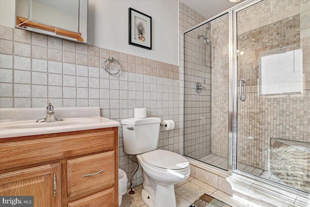 bathroom featuring tile patterned floors, vanity, a shower with door, and tile walls