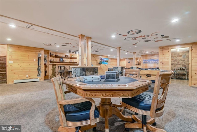 carpeted dining space with baseboard heating and wood walls