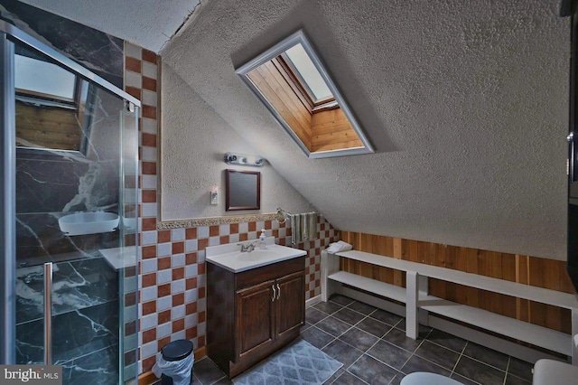 bathroom featuring tile patterned floors, a textured ceiling, a shower with door, vanity, and vaulted ceiling with skylight