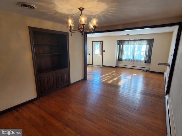 spare room featuring a baseboard radiator, dark hardwood / wood-style floors, and a chandelier