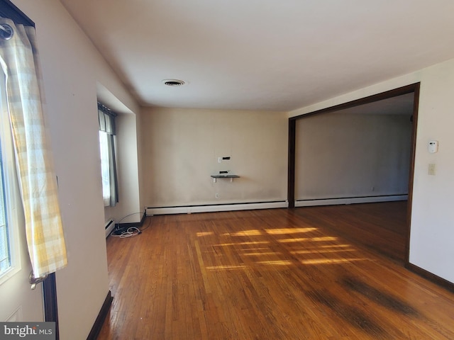 empty room with plenty of natural light, dark hardwood / wood-style flooring, and baseboard heating