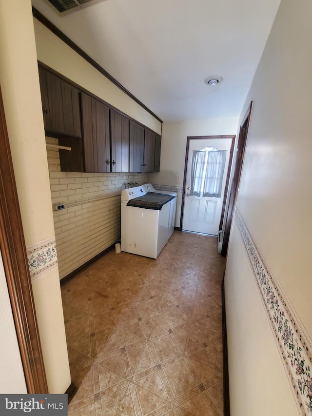 washroom with cabinets, brick wall, and washer / dryer