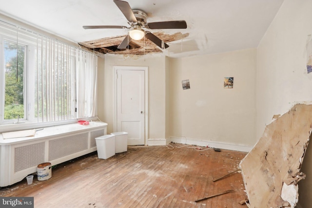 laundry room featuring ceiling fan, wood-type flooring, and radiator heating unit