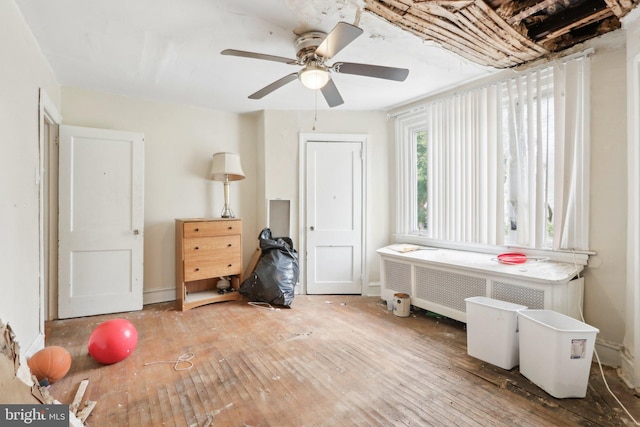 misc room featuring ceiling fan, radiator heating unit, and wood-type flooring