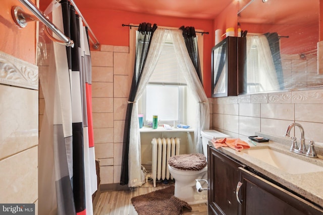 bathroom with radiator heating unit, hardwood / wood-style floors, toilet, decorative backsplash, and vanity