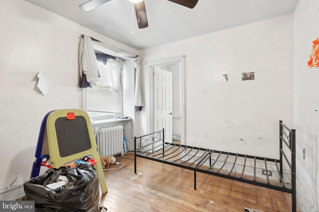 bedroom featuring ceiling fan, radiator heating unit, and hardwood / wood-style flooring