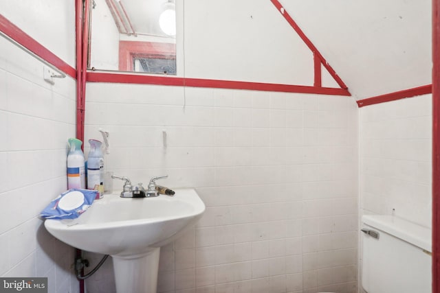 bathroom with toilet and tile walls