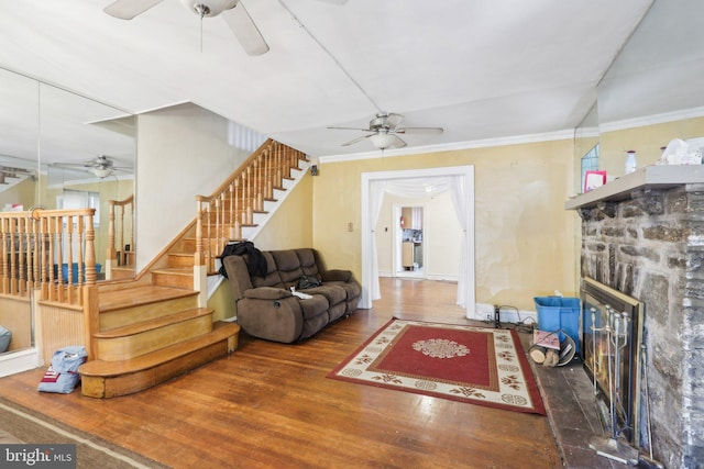 living room with dark hardwood / wood-style floors, a stone fireplace, and crown molding