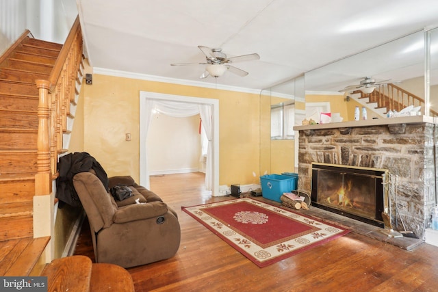 living room with hardwood / wood-style flooring, ceiling fan, ornamental molding, and a fireplace