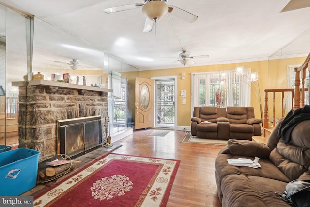 living room with hardwood / wood-style flooring, a stone fireplace, and crown molding