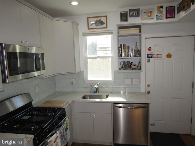 kitchen with light stone countertops, appliances with stainless steel finishes, white cabinets, and sink