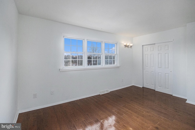 unfurnished bedroom with dark hardwood / wood-style floors and a closet