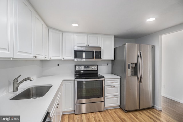 kitchen with white cabinets, light wood-type flooring, sink, and appliances with stainless steel finishes