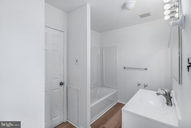 bathroom with hardwood / wood-style flooring, vanity, and shower / bath combination