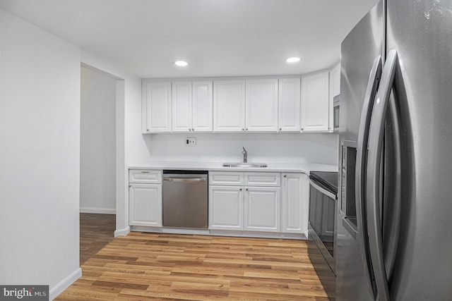 kitchen with white cabinetry, sink, light hardwood / wood-style flooring, and appliances with stainless steel finishes